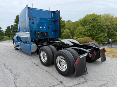 Truck chassis and rear cab of a blue 2024 International LT625 tractor showing dual rear axles and mud flaps.
