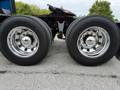 Dual tractor-trailer rear wheels with polished chrome hubcaps and black chassis; no legible text on image besides wheel branding.