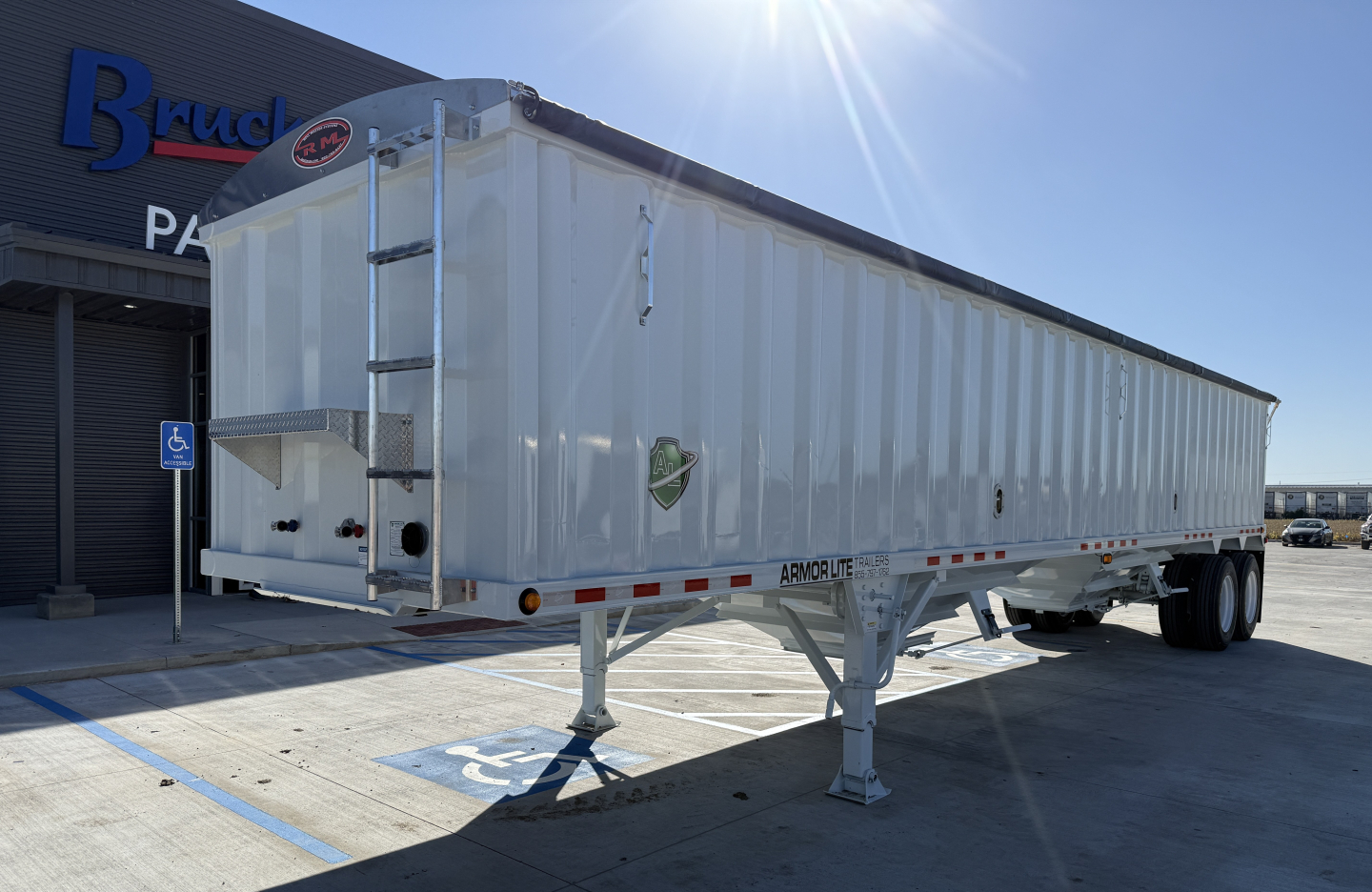 Armor Lite 40' steel grain hopper trailer in a dealership lot showing front landing gear and side label warnings.