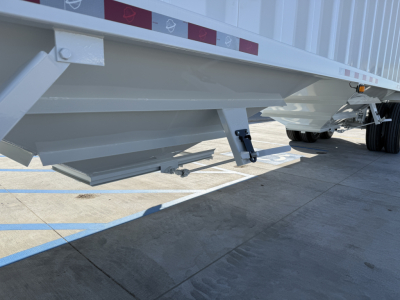 Trailer underside showing steel grain hopper with accessible support brackets and frame rail.