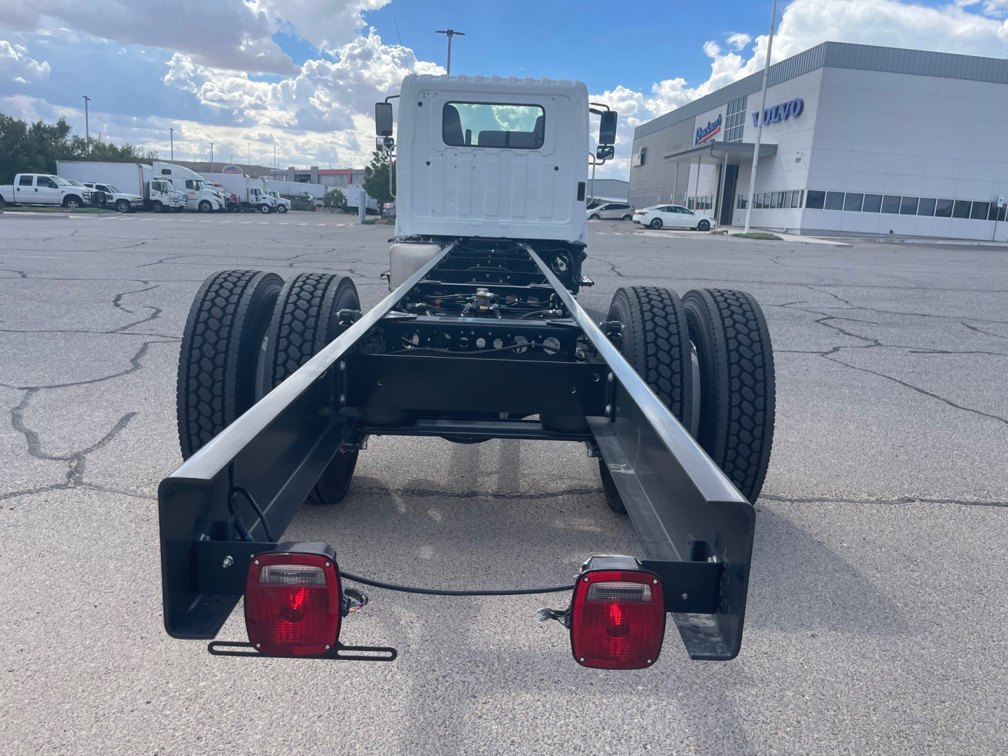 Chassis rear view of a new 2025 Hino L6 cab and chassis showing dual rear axles, frame rails, taillights, and rear bumper assemblies.