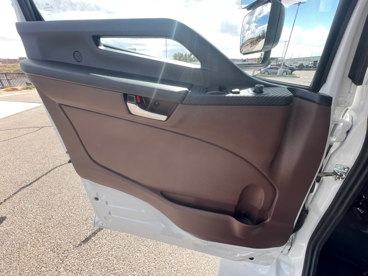 Truck door panel with brown interior, window controls, and door handle; partial exterior white body visible