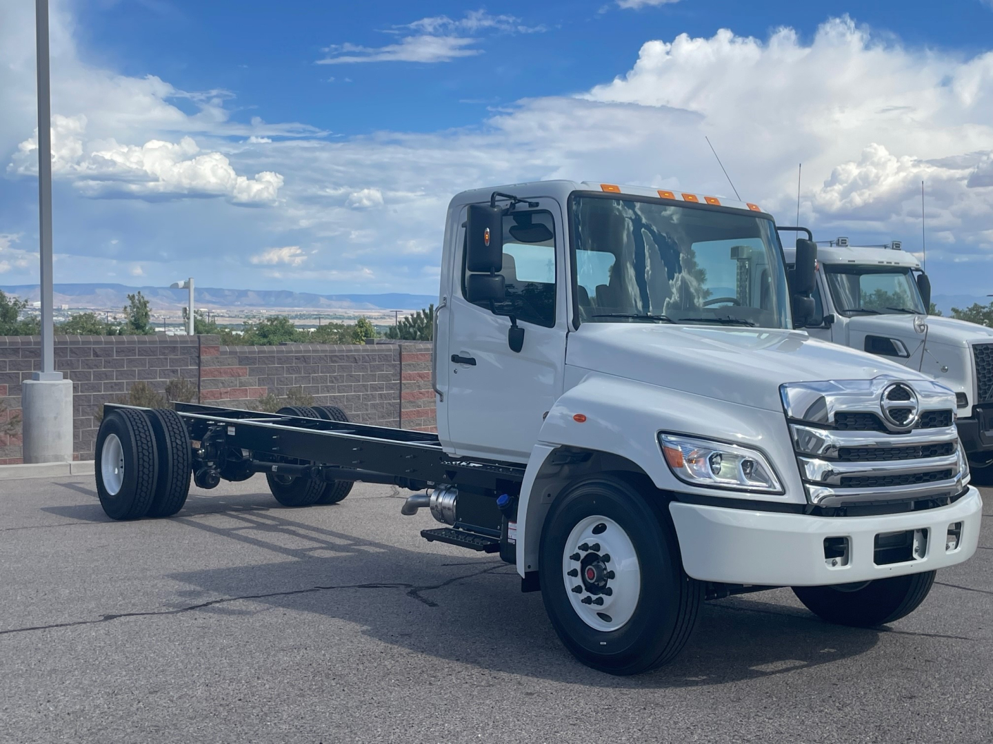 New 2025 Hino L6 cab chassis truck in a lot showing front and side view with chassis rails and dual rear wheels.