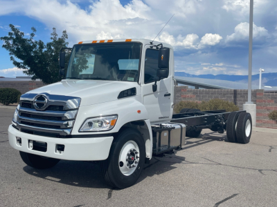 Truck cab and chassis showing front grille, headlights, and wheel on white 2025 Hino L6 chassis with exposed chassis rails
