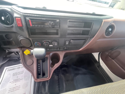 Cab and dashboard of a 2025 Hino L6 truck showing center console, gear shifter, climate controls, and cup holders.
