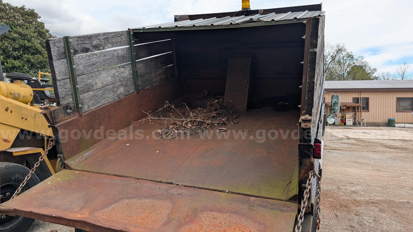 Dump truck bed of a 1990 International 4700 with open rear cargo area showing rusty floor and wood sides.