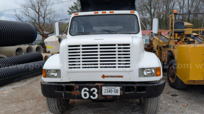 International 4700 dump truck front view showing white cab, grille, bumper, headlamps, and license plate with number 63.
