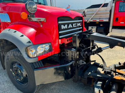 Front-left view of a red Mack Granite plow truck showing Mack grille and hood; hydraulic plow mounting frame and black bumper components visible.