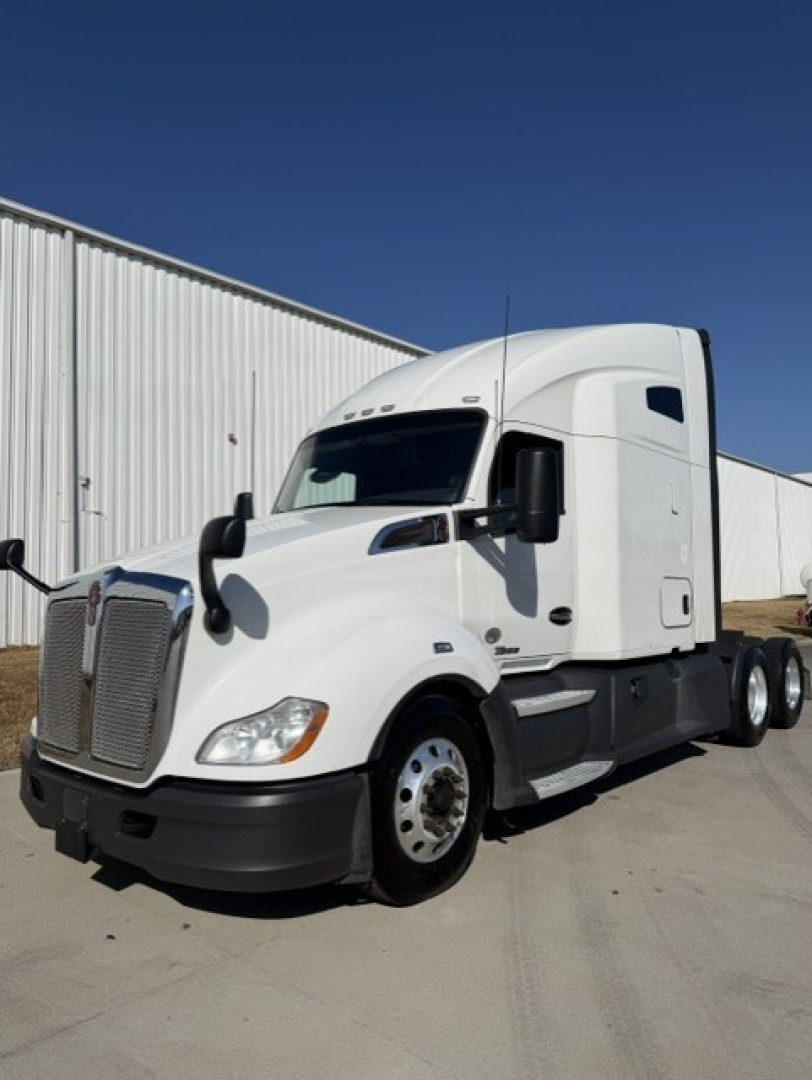 Kenworth T680 tractor-trailer cab in white, side view, showing front grille, aerodynamic mirrors, and sleeper cabin.