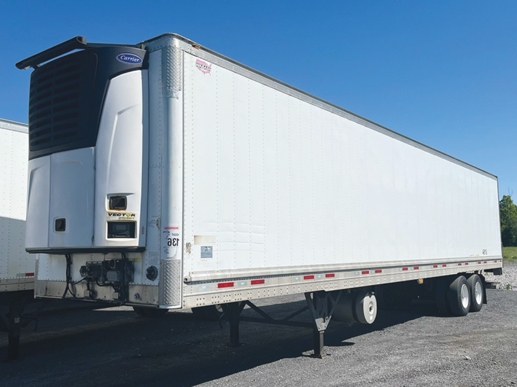 Trailer side view showing a white 2019 Wabash aluminum reefer trailer with a Carrier refrigeration unit at the front left; dual axles with reflective tape along the lower edge.