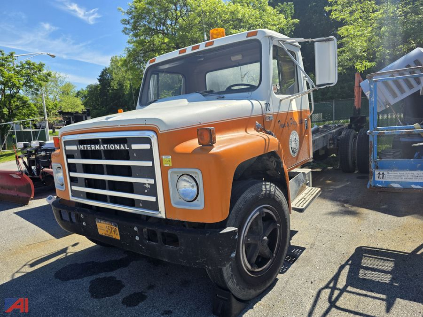 International 1700 chassis cab side angle showing orange and white cab with black grille and lettering 'INTERNATIONAL' on the front, CDL badge on door, used truck.