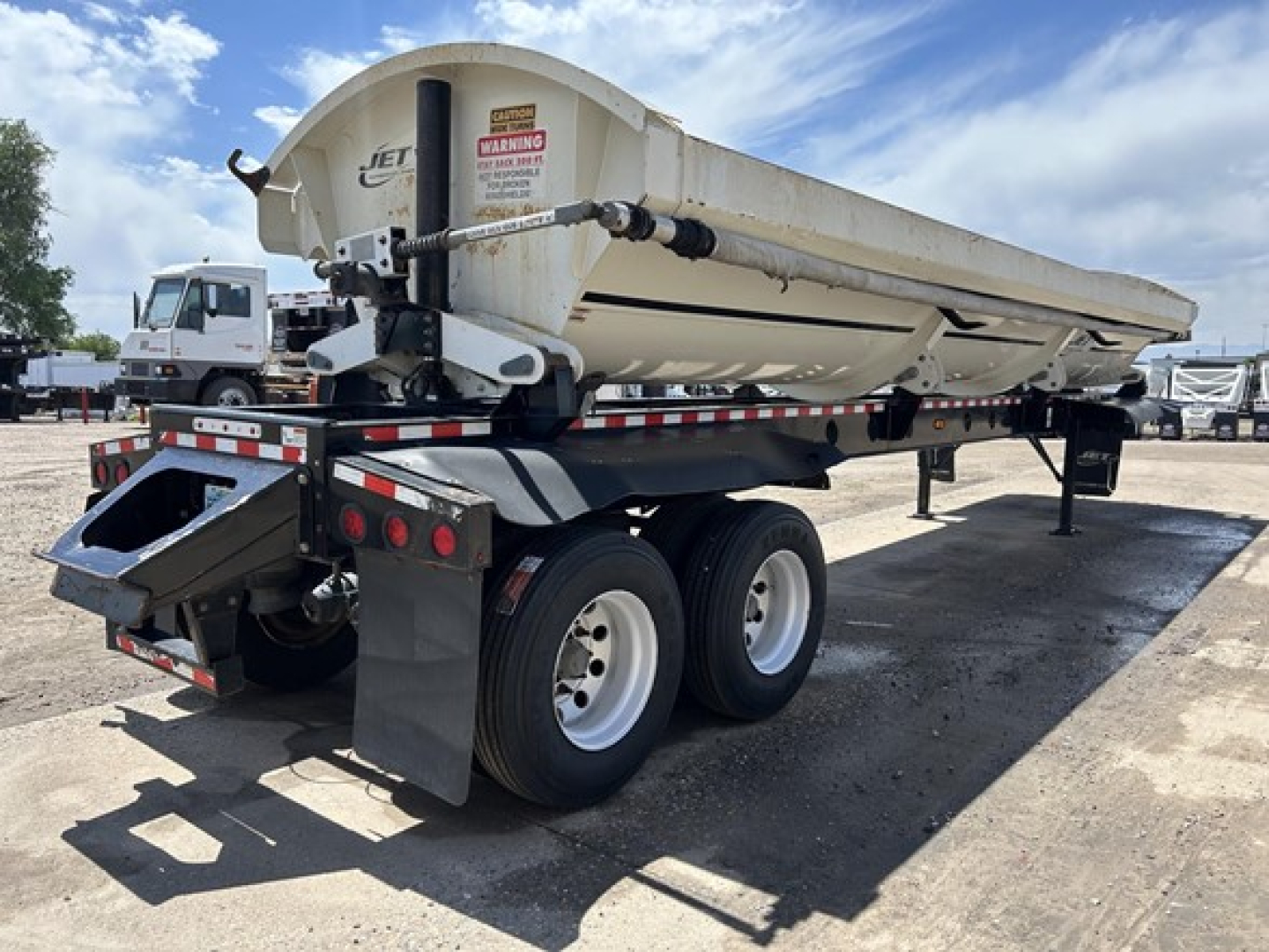 Jet Air Ride side dump trailer showing rear and left side with hydraulic hoist and dual-axle wheels.