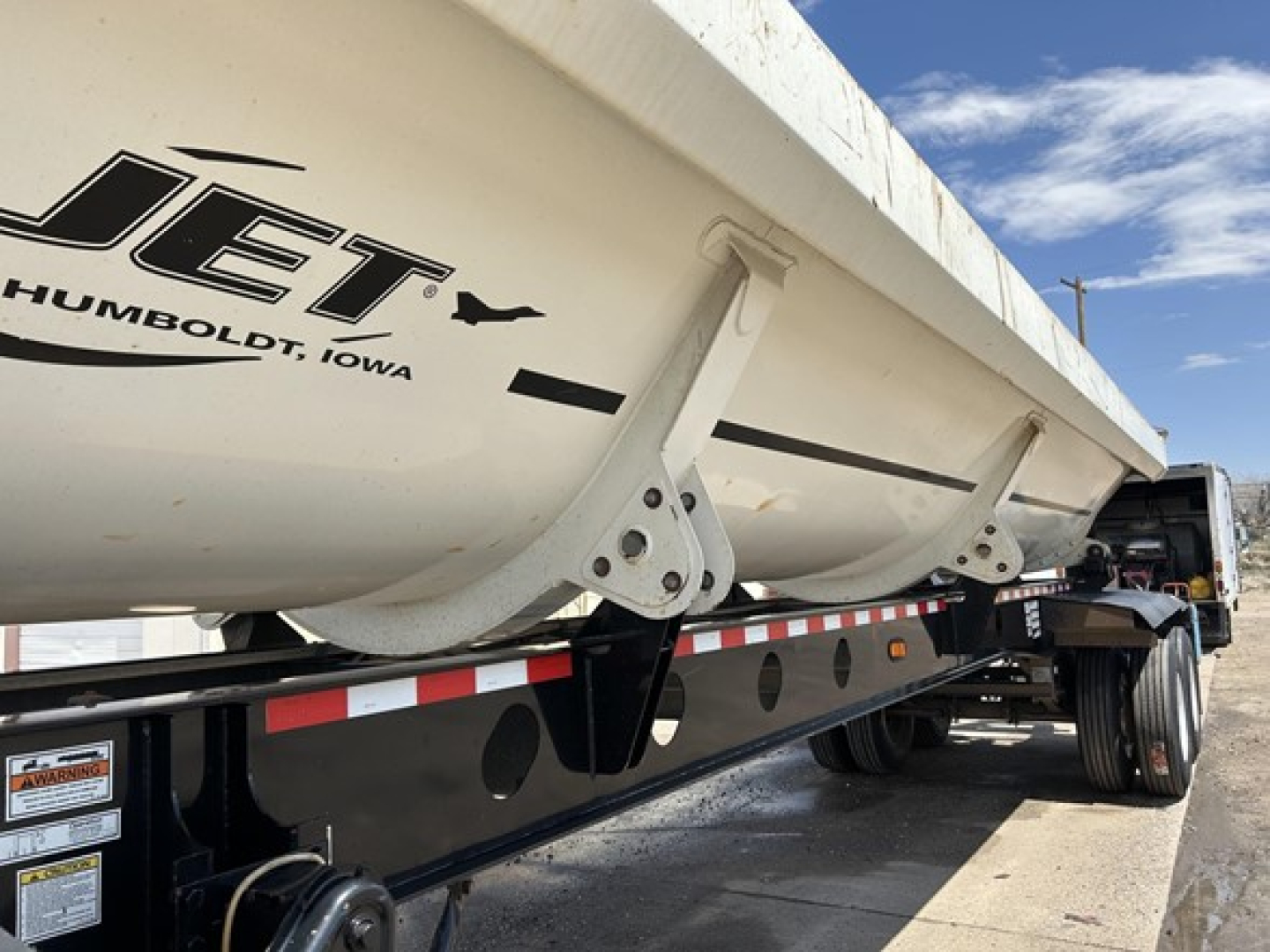 Jet air ride side dump trailer showing Jet Humboldt, Iowa logo on aluminum side and underside of trailer with frame rails and wheels.