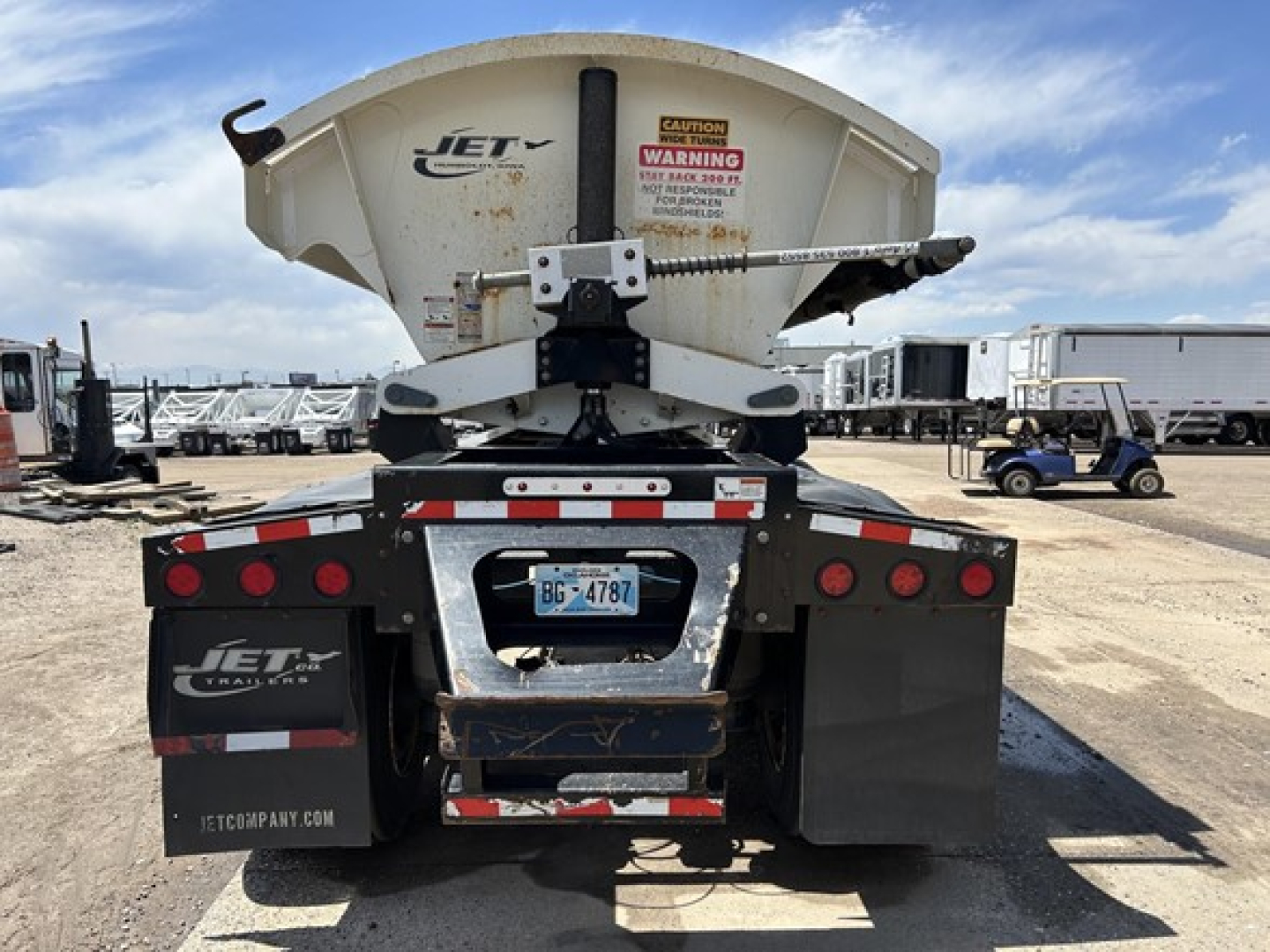 Jet side-dump trailer rear view showing warning label and brake lights.