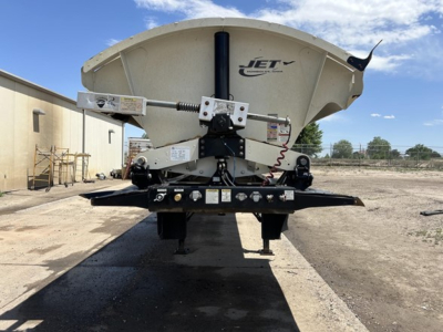 Jet brand side-dump trailer back view showing hydraulic lift and scattered components with Jet logo on hopper.