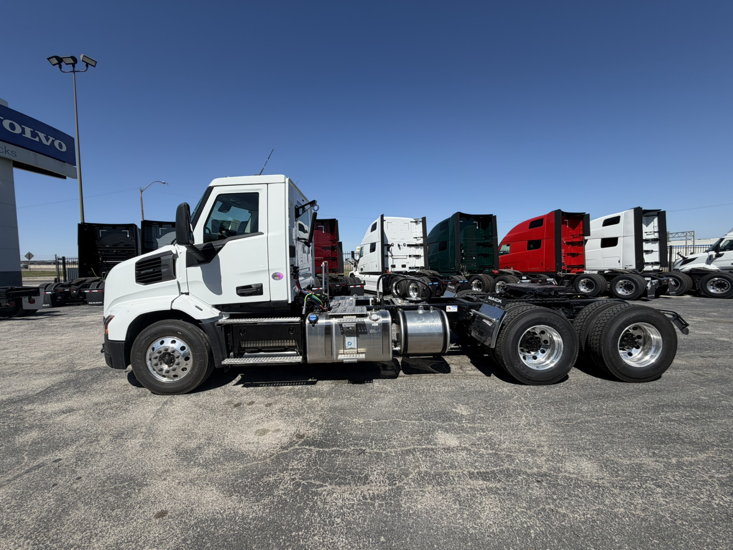 Truck side view showing 2027 Mack AN64T conventional daycab with dual rear axles and chrome fuel tanks.