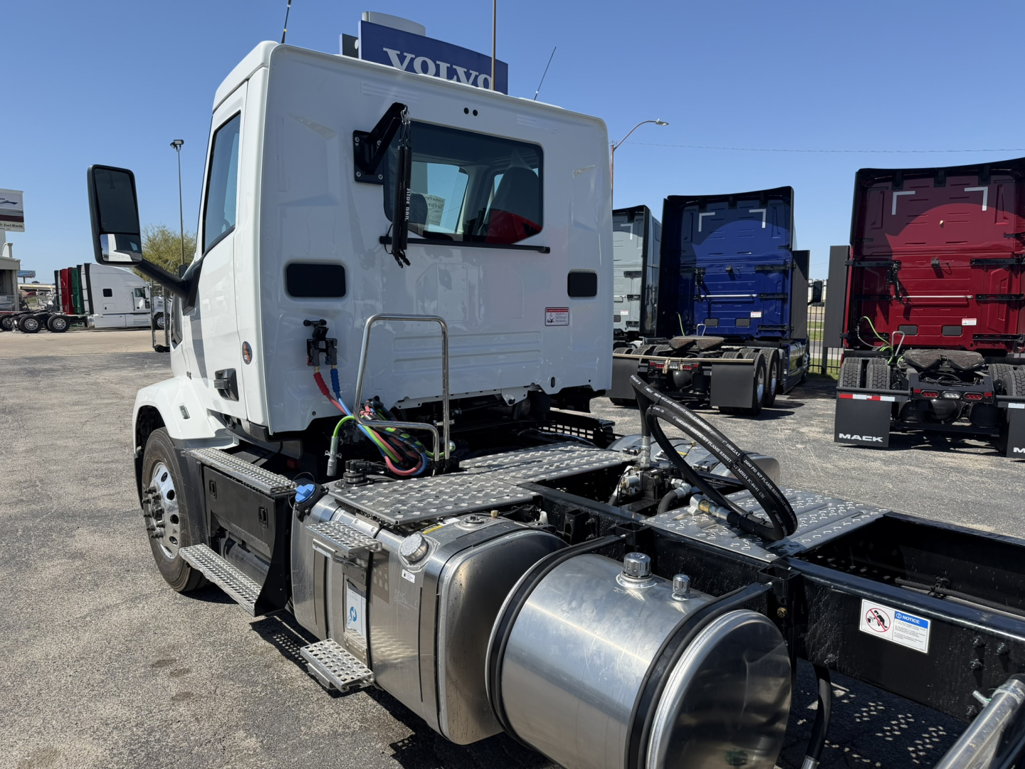Truck cab and chassis of a 2027 Mack AN64T daycab showing engine bay area with fuel tanks and wiring harness.