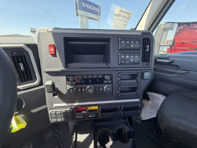 Dashboard interior of 2027 Mack AN64T showing steering column, control panels, climate controls, and storage compartments.