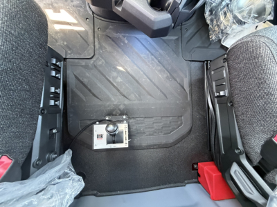 Cab floor of a Mack AN64T truck showing a floor-mounted control lever and rubber mat with diagonal grooves.