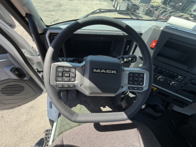 Mack AN64T truck interior showing steering wheel with Mack logo, dashboard controls on both sides, gear shifter, and center console.