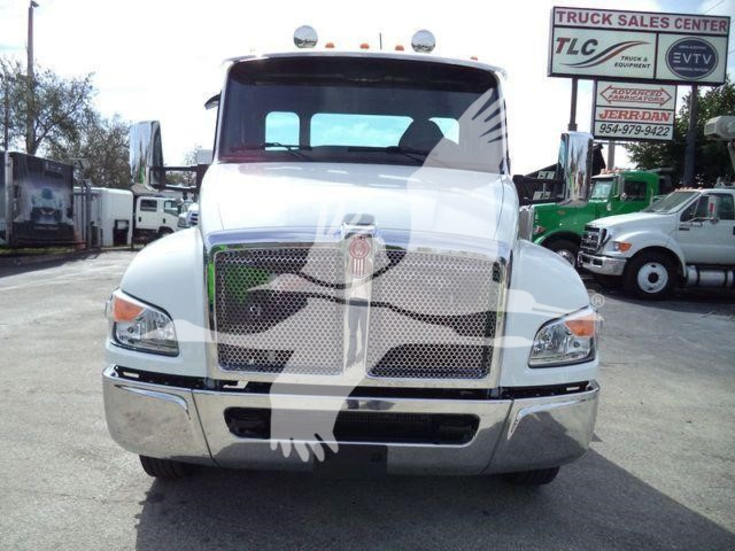 Kenworth T280 rollback truck front view with chrome grille and bumper, white cab, dealership lot in background.