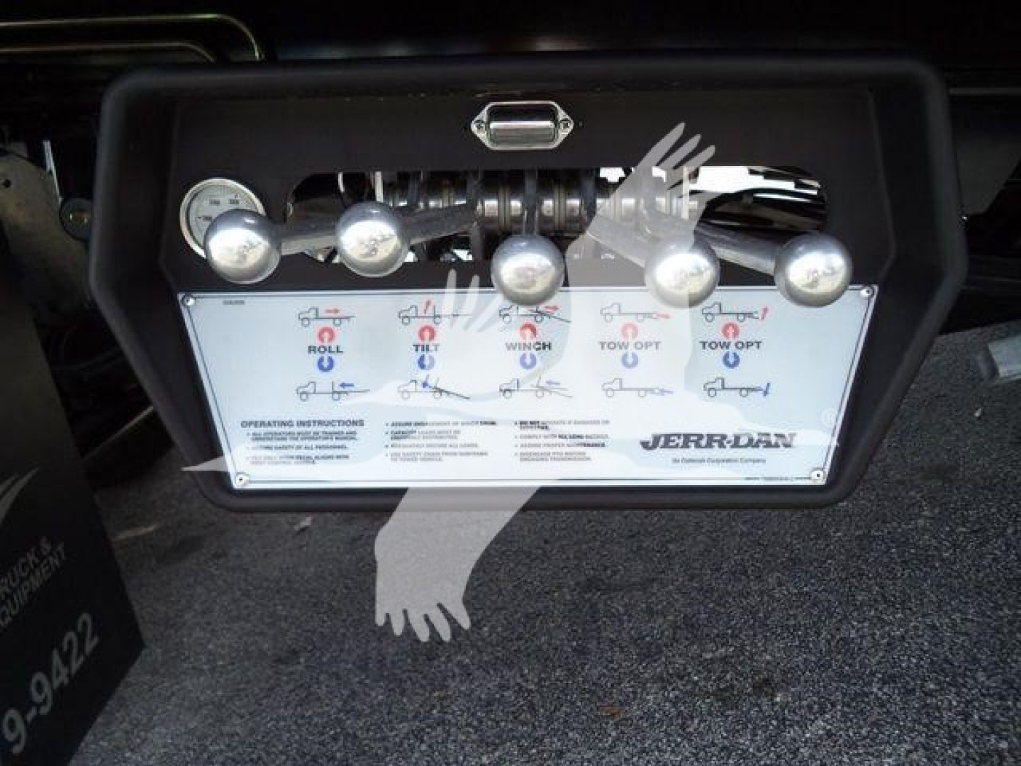Kenworth rollback control panel showing levers labeled Roll, Tilt, Wing, and Tow options with brand JERR-DAN; includes operating instructions and gauges.