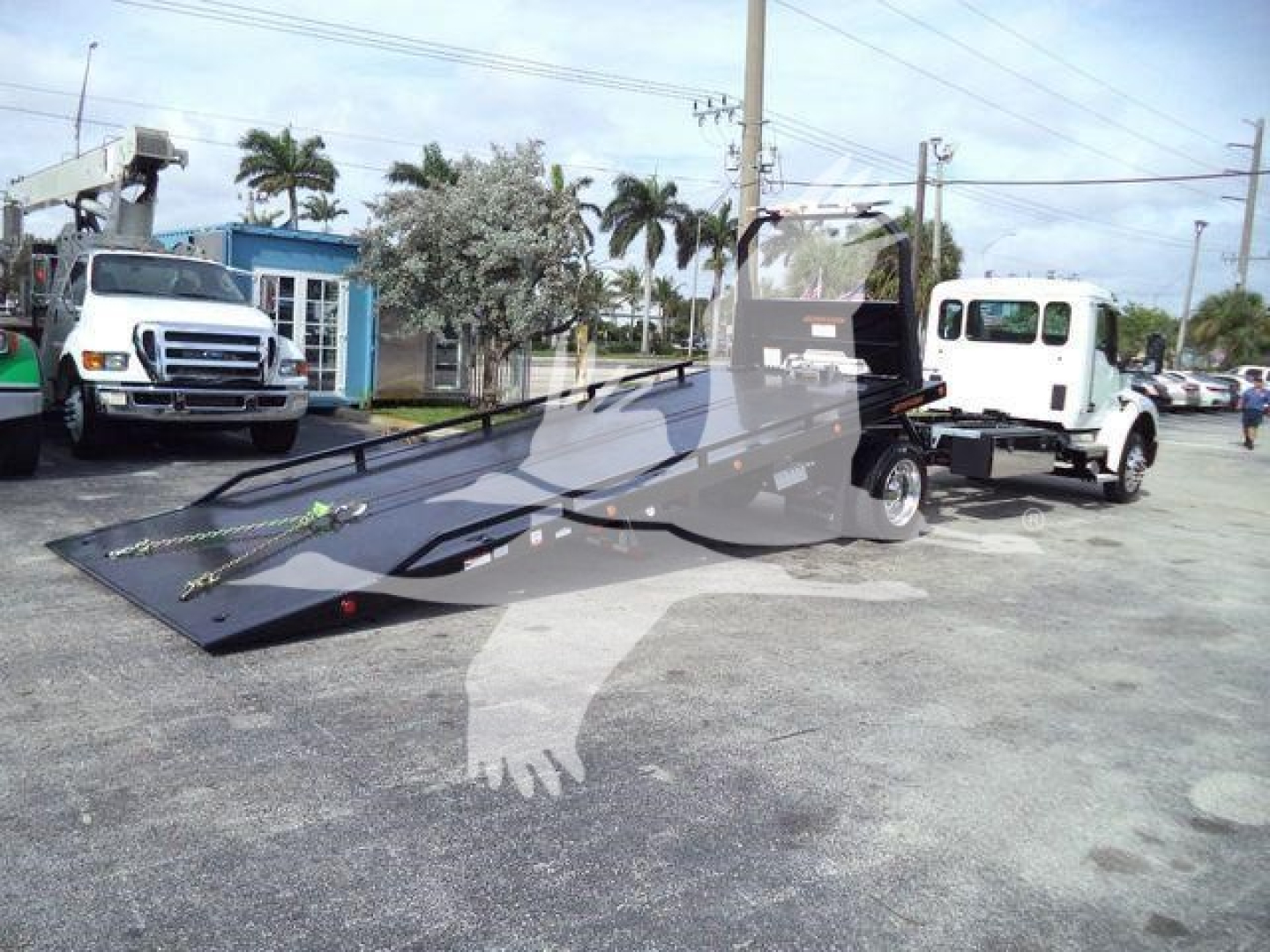 Tow truck 2025 Kenworth T280 rollback flatbed with lowered bed and tow equipment, white cab, black metal bed, outdoor lot.