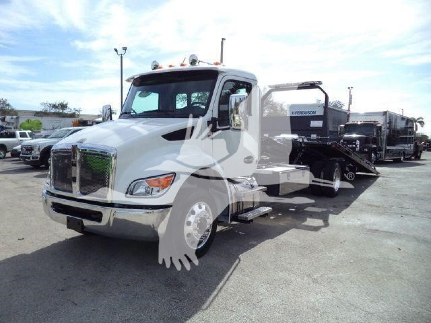 Kenworth T280 rollback tow truck in a lot, front grille and cab visible with a hydraulic bed trailer attached; no legible technical labels visible on the image.