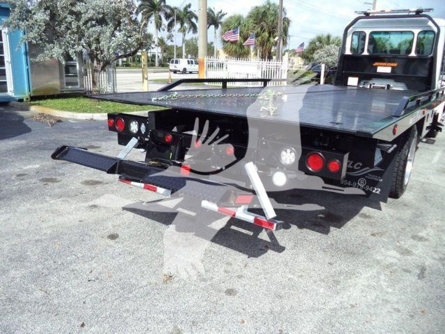 Kenworth rollback truck bed with rear loading ramps and hydraulic system, showing platform and tail lights.