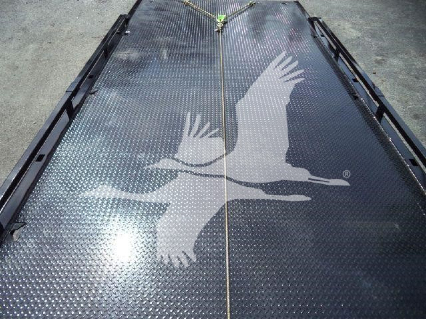 Kenworth truck bed with textured diamond plate surface and a hoist attachment; large white eagle graphic across the surface.