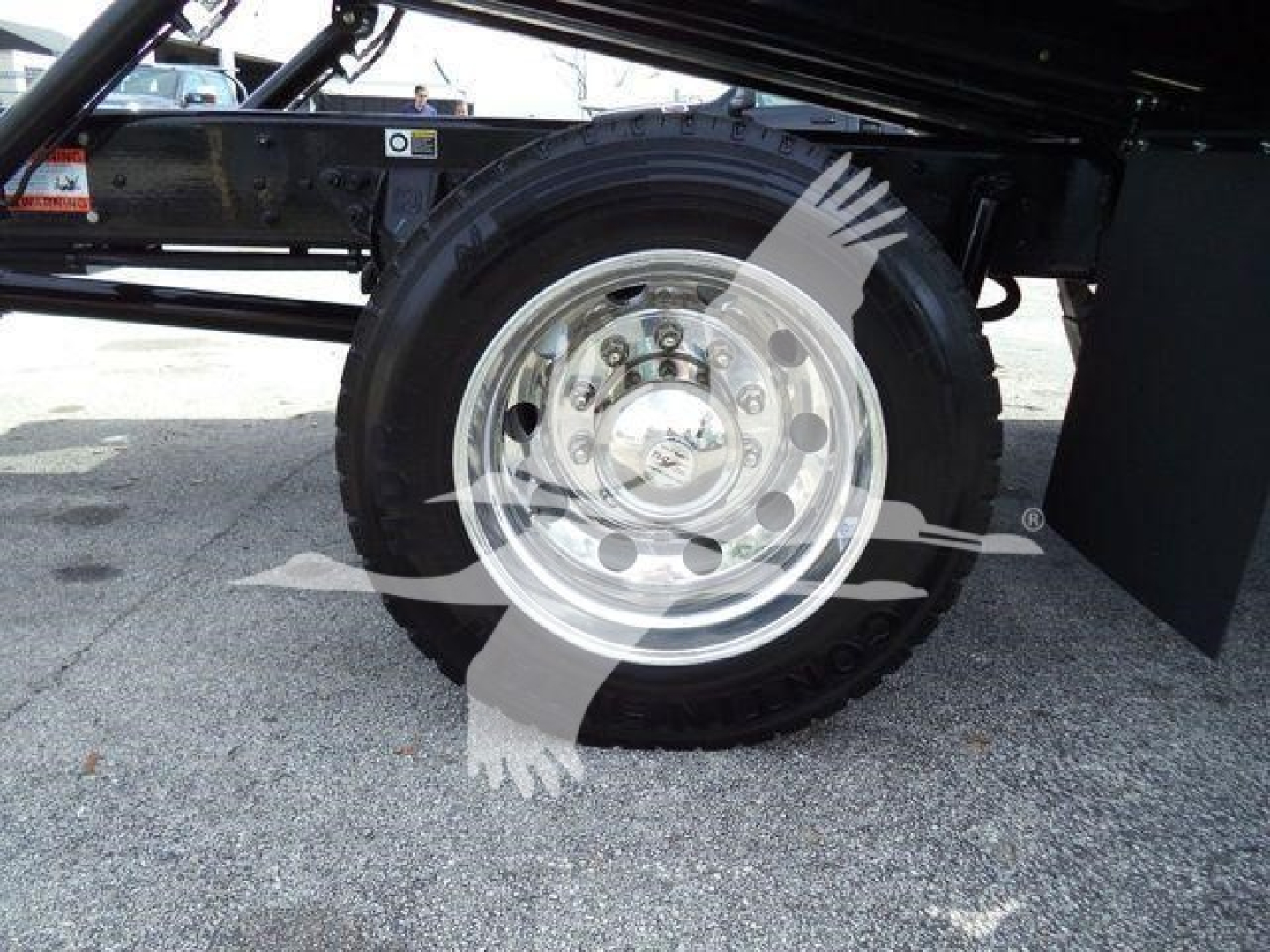 Trailer truck wheel and suspension view showing chrome steel wheel and tire on Kenworth T280 rollback chassis.