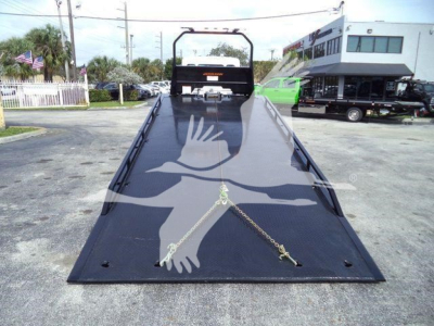 Flatbed tow truck bed with ramps and winch area, front view, truck with loading deck extended.