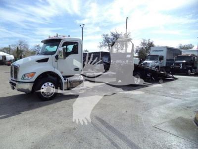 Kenworth truck in a rollback configuration showing cab and flatbed with equipment behind the cab.