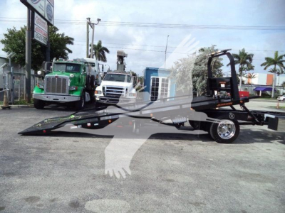 Kenworth T280 rollback truck with flatbed lift and tow equipment, front green truck in background, dealership lot.