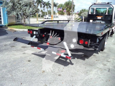 Kenworth rollback truck bed with rear loading ramps and hydraulic system, showing platform and tail lights.