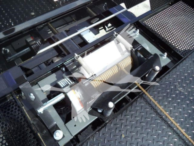 Kenworth truck rollback mechanism showing winch and steel cable assembly with metal mount and hydraulic components.
