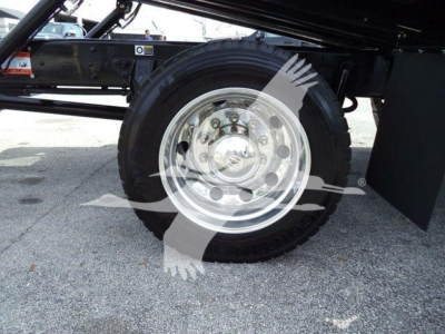 Trailer truck wheel and suspension view showing chrome steel wheel and tire on Kenworth T280 rollback chassis.