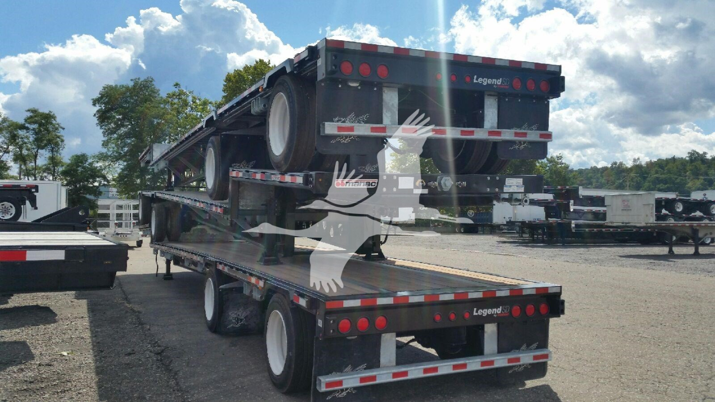 Manac dropdeck trailer showing dual rear ramps and stacked trailers in yard, with VIN and stock number not visible on tag.