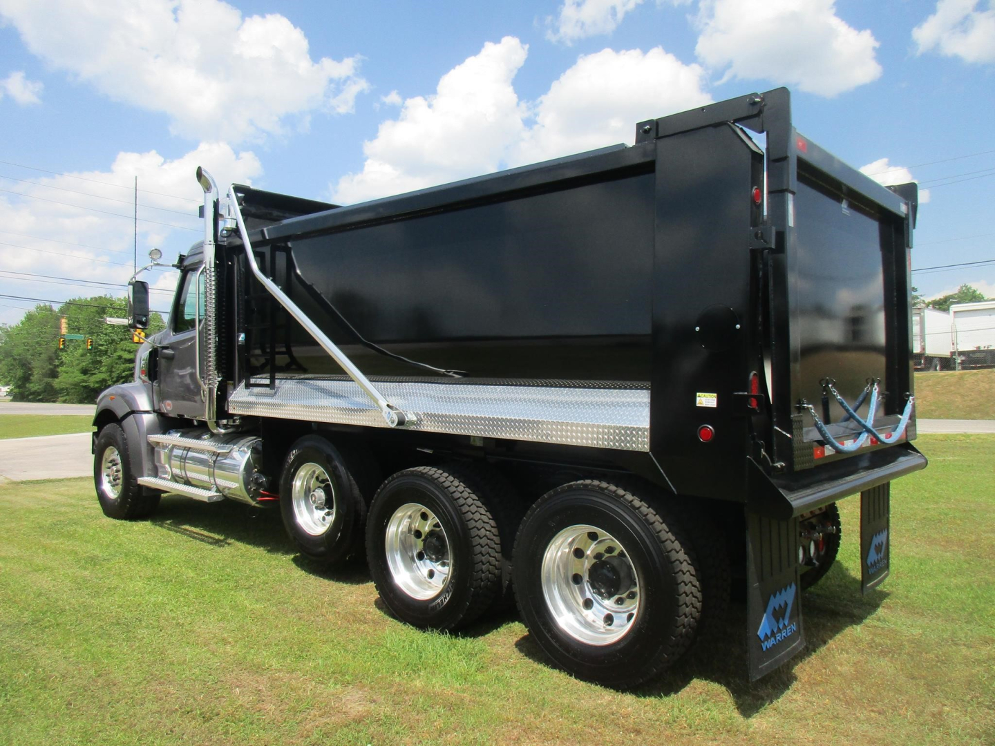 Western Star 49X dump truck side view showing black dump bed and chrome wheels with dual rear axles