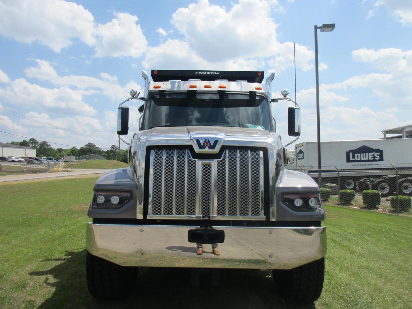 Western Star 49X dump truck front view showing chrome grille, headlights, and bumper with windshield visor; black sun visor above cab and low-angle perspective.