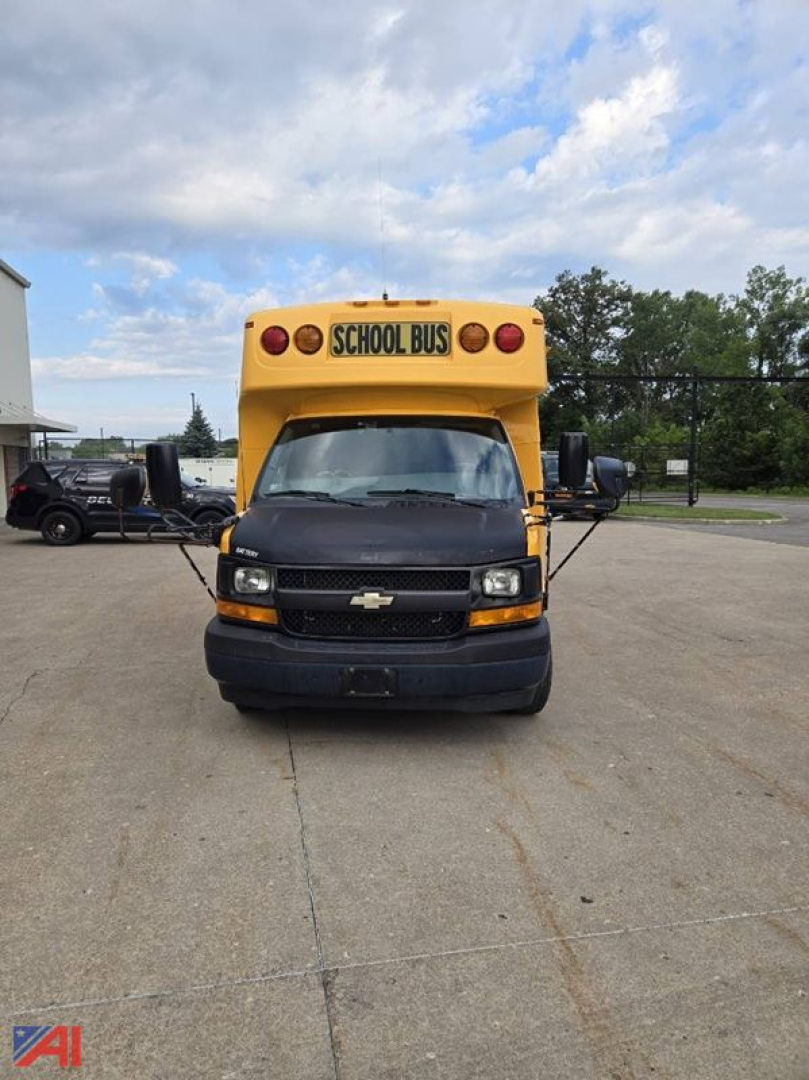 Front view of a yellow 2017 Chevrolet Express G4500 school bus with black bumper, round red lights, and a sign reading SCHOOL BUS on the top of the cab.