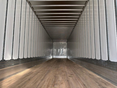Trailer interior showing long wooden floor and metal sidewalls with ribbed ceiling.