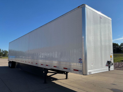 Trailer side view: silver box-style utility trailer with hitch at front, raised landing gear, and reflective safety markings along the lower edge.