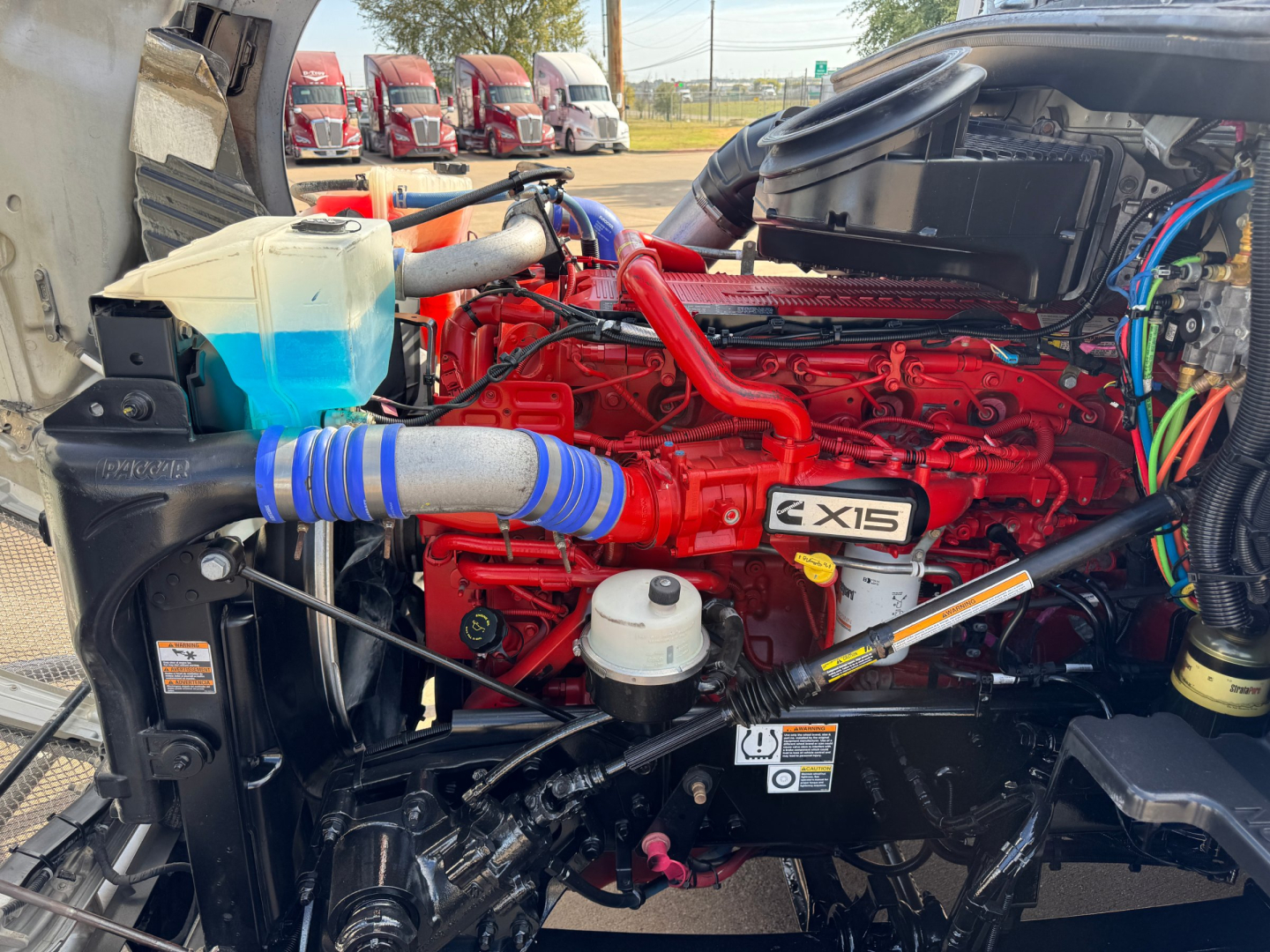 Kenworth T680 engine bay showing red X15 diesel engine and surrounding components