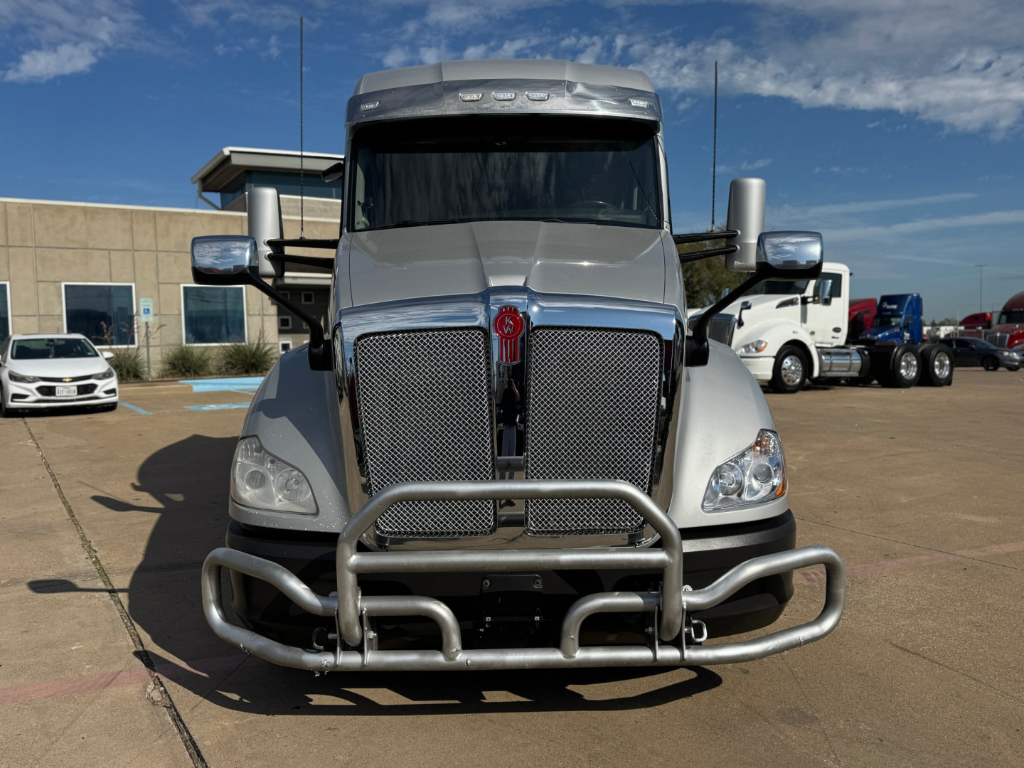 Kenworth T680 front view showing large grille, bumper guard, and dual chrome exhaust stacks. Visible text includes no legible labels on the bumper; general truck silhouette.
