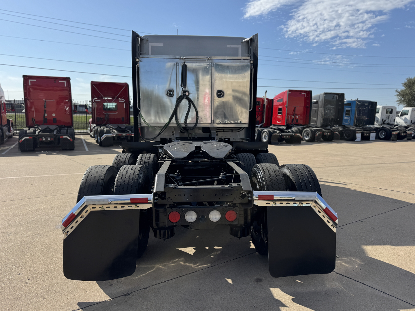 Kenworth T680 tractor rear view showing fifth wheel, dual rear axles, and mud flaps.