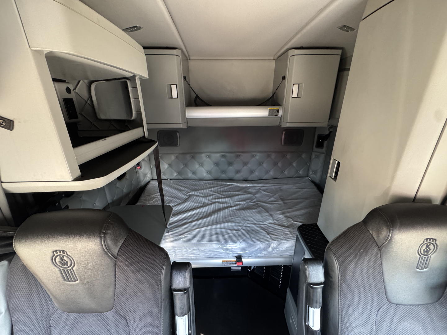 Kenworth T680 sleeper cab interior showing bunk bed area and storage cabinets.