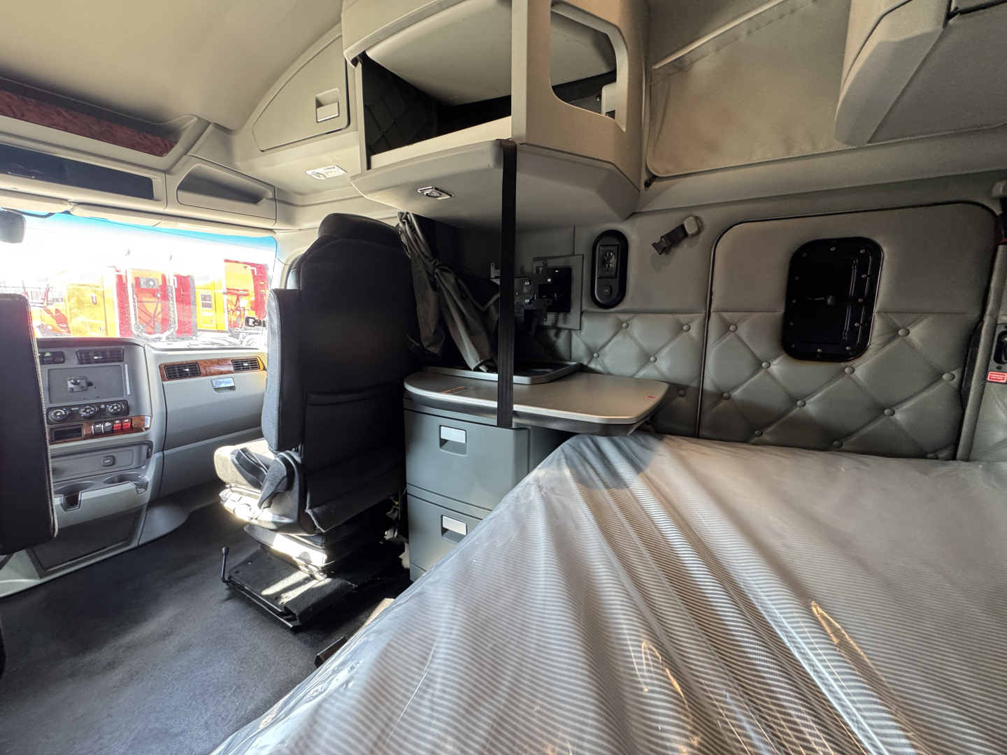 Kenworth truck sleeper cab interior showing bunk bed and storage cabinets.