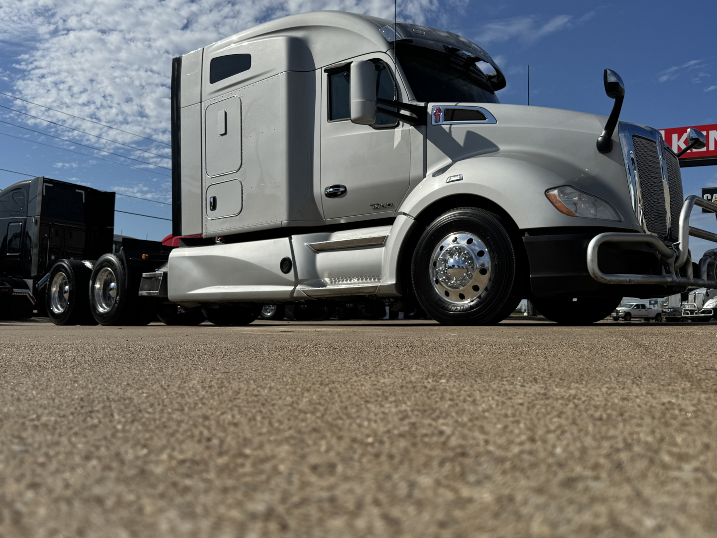 Kenworth T680 sleeper tractor tractor cab side view showing chrome wheels and aerodynamic mirrors.