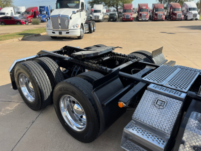 Kenworth T680 chassis showing dual rear axles and chrome fuel/tank area with diamond plate toolbox and steps.